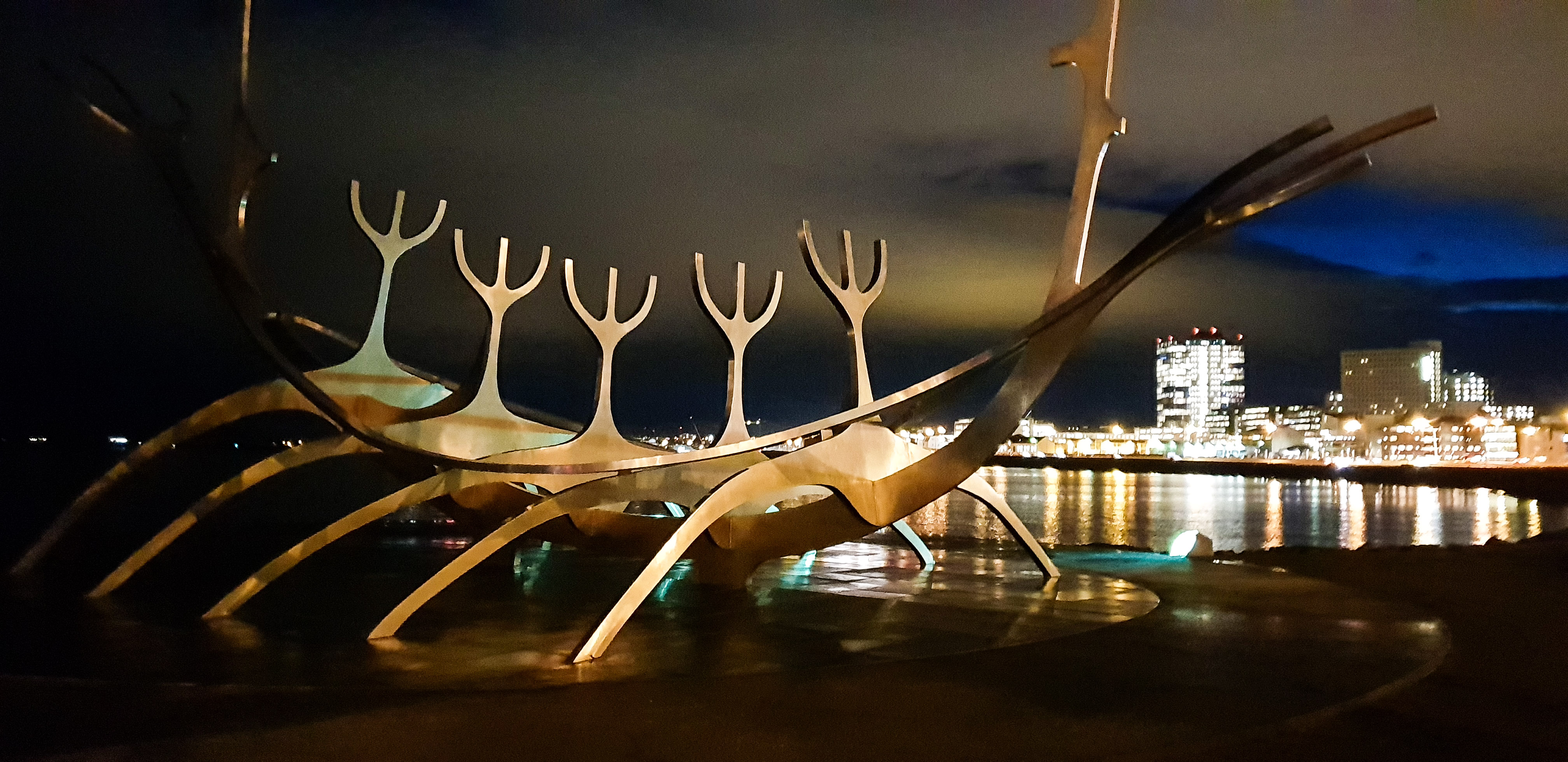 The Sun Voyager in Reykjavik illuminated with the city lights in the back.