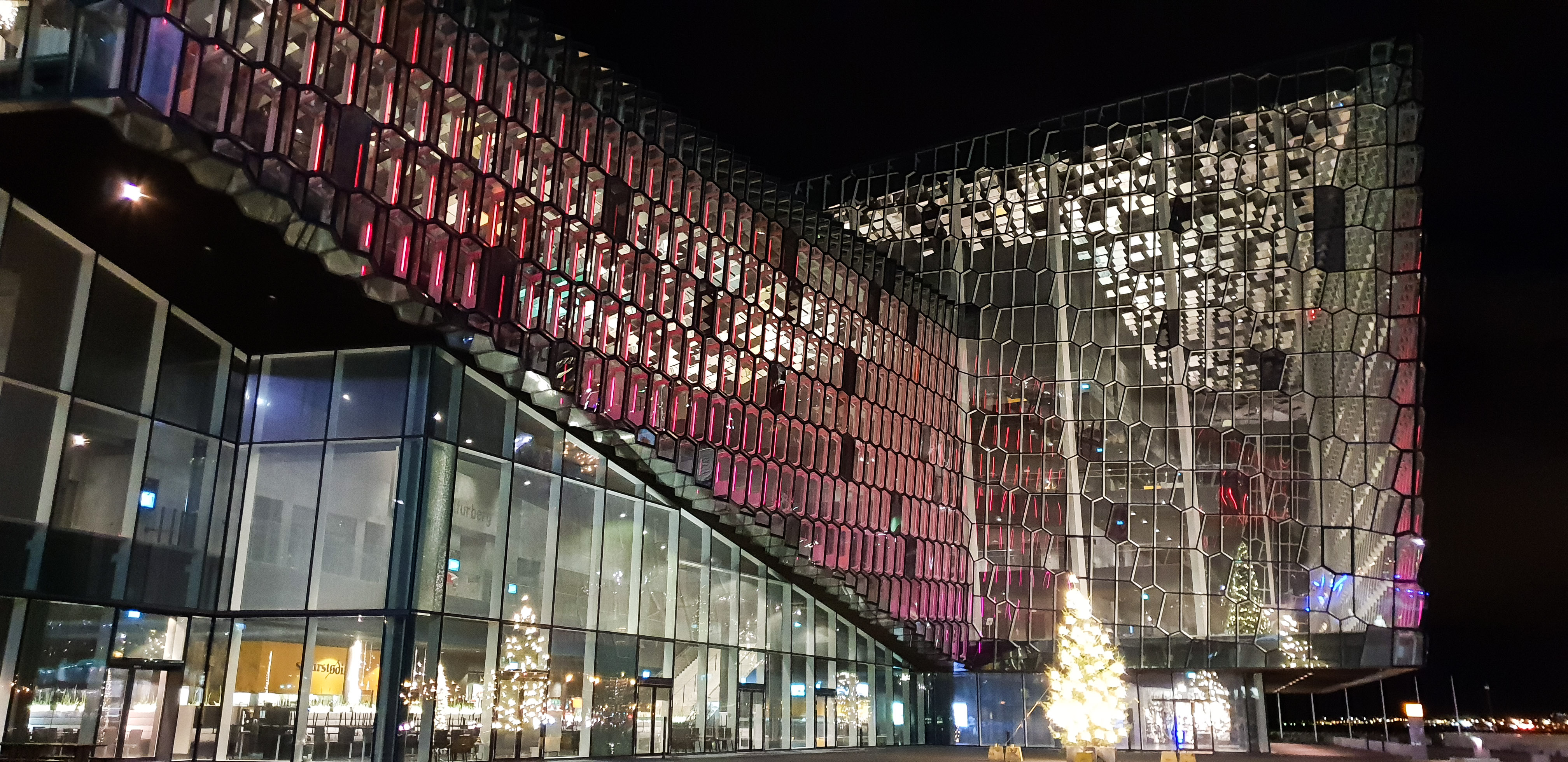 Reykjavik Concert Hall Harpa with pink and with light moving along the facade.