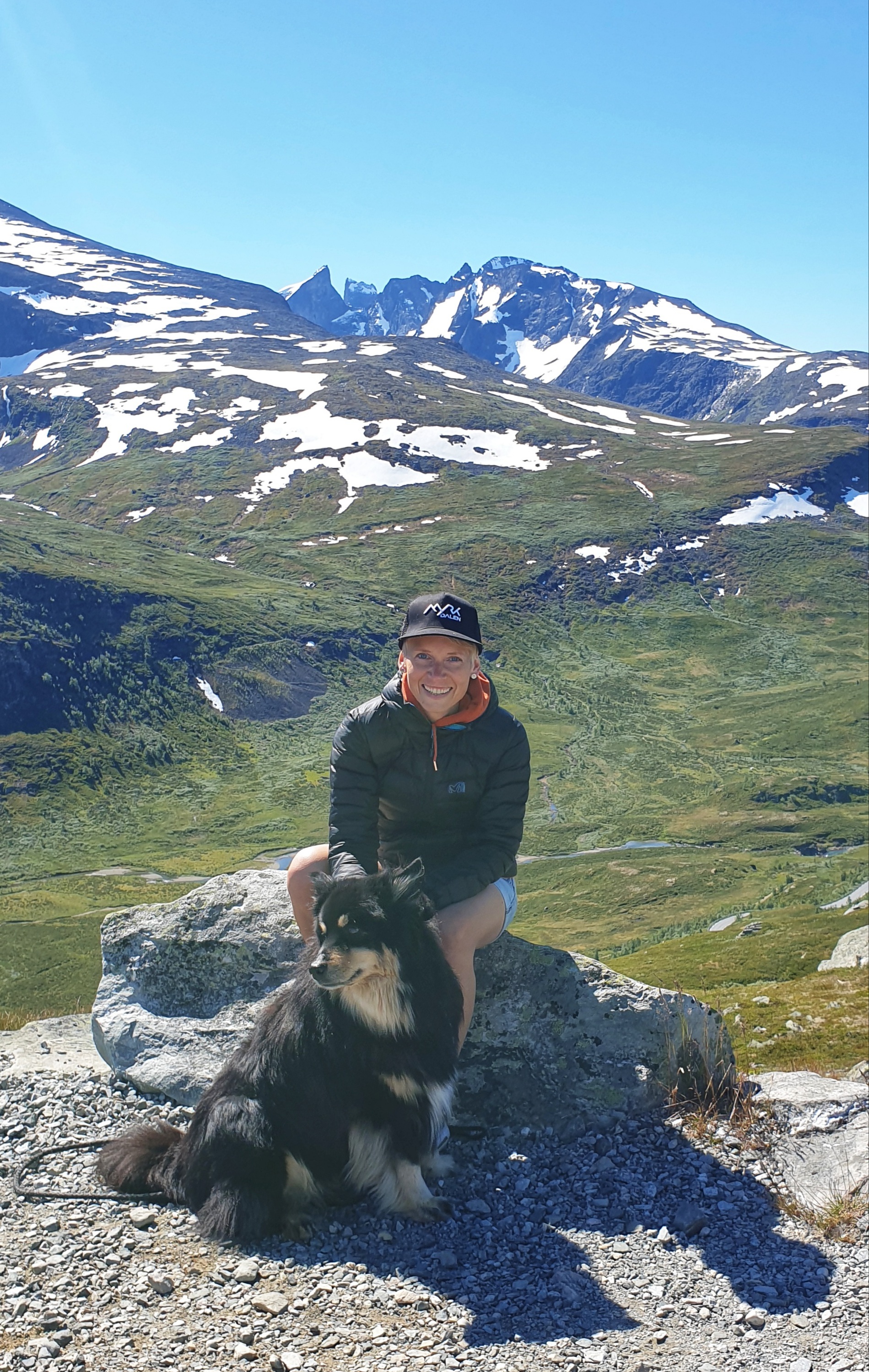 A smiling woman and dog in front of Hurrungane mountains
