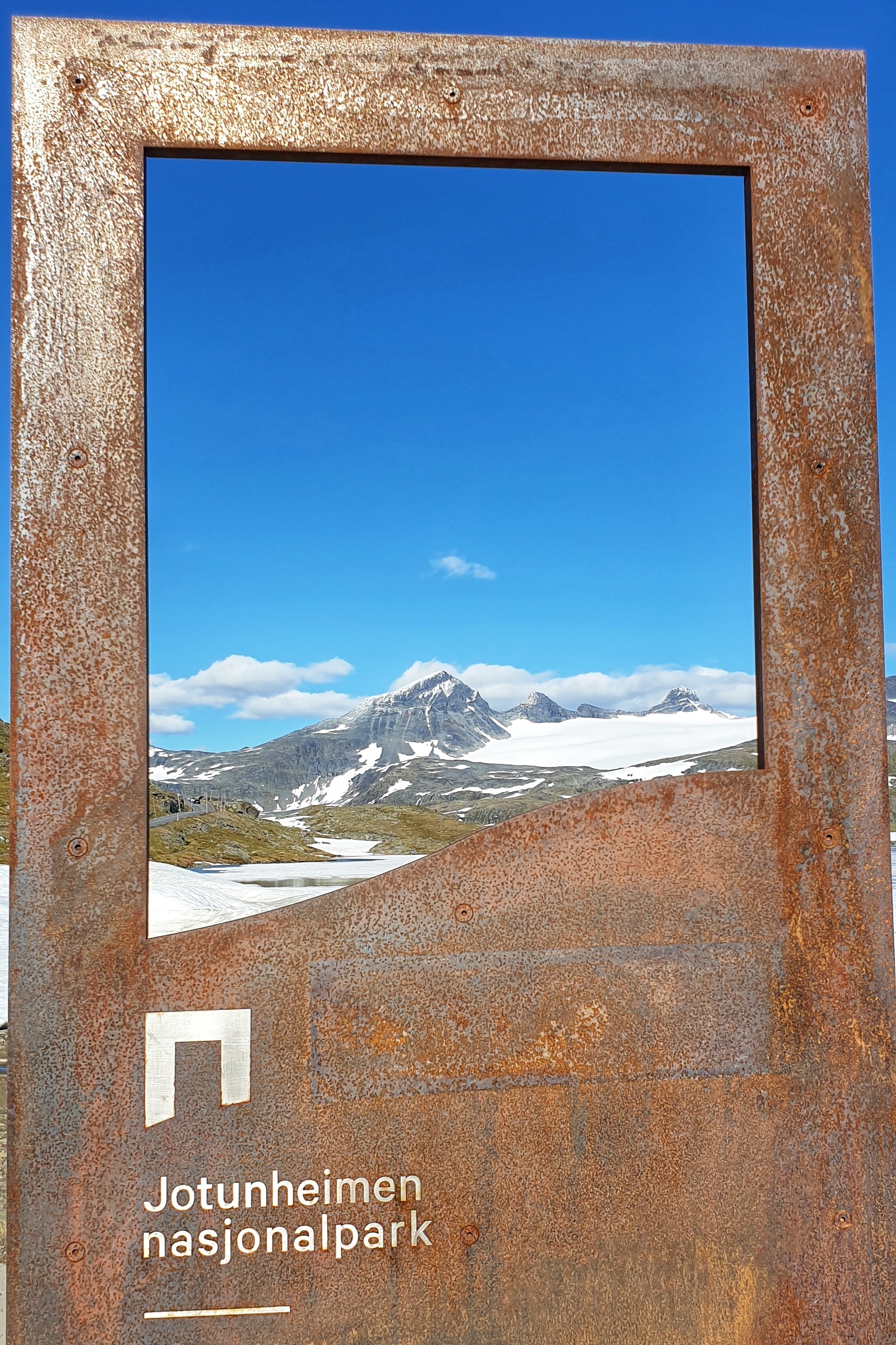 SmØrstabbtindane seen through a Jotunheimen National Park sign