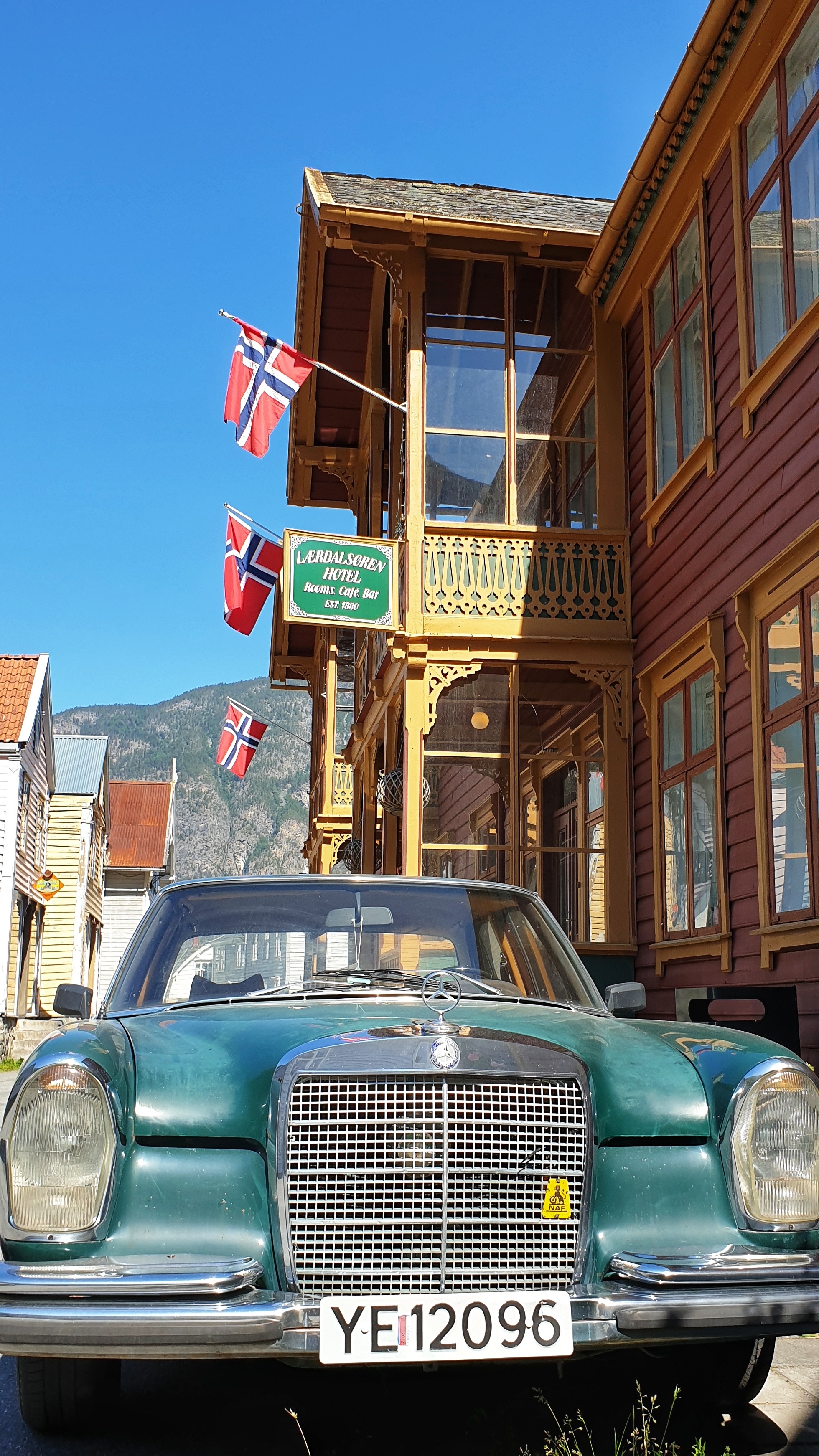 A green veteran car outside a red swiss style hotel in old LÆrdalsØyri