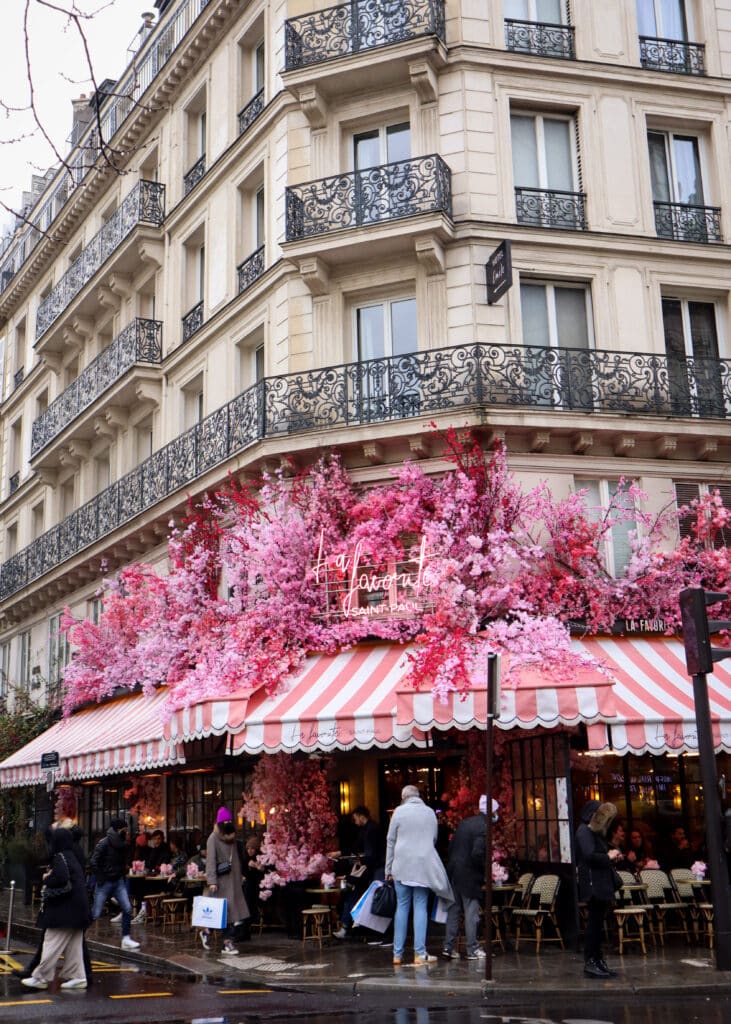 Large decorations of pink flowers on a restaurant in an historic building in Paris.