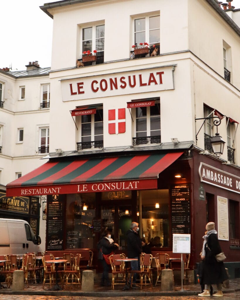 Three people outside Le Consulat restaurant in Paris.