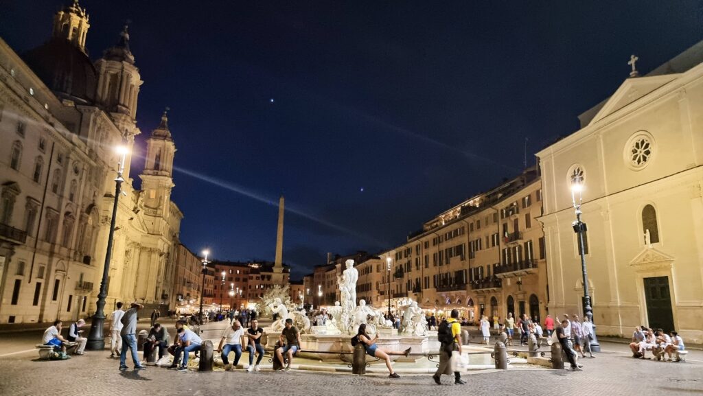 A square with fountains in Rome at night.