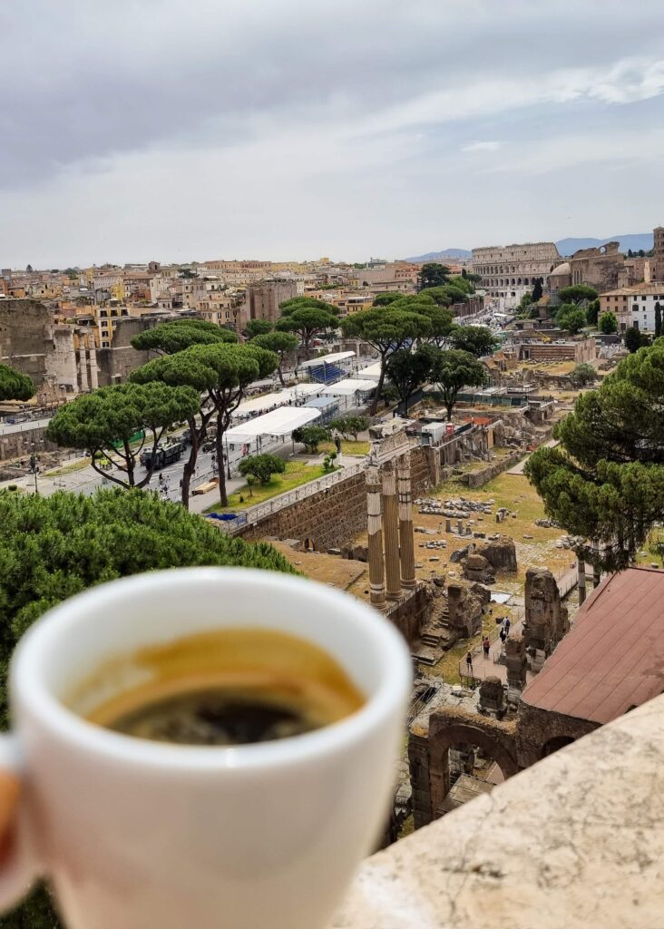 A coffee cup in front of views towards the Colosseum in Rome.