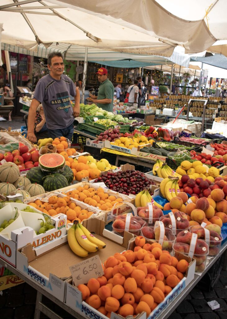 A man standing behind his fruit stall on a market in Rome.