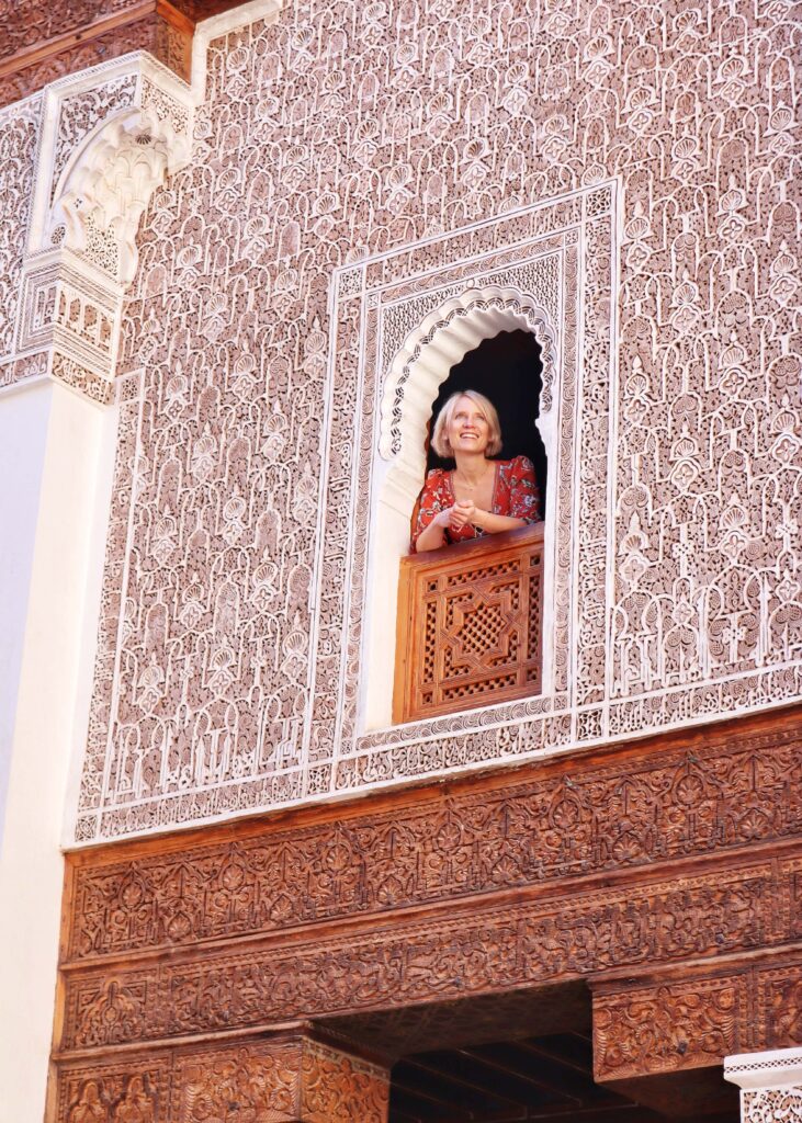 A woman looking out of a window at Ben Youssef Madrasa in Marrakech during 1 week in Morocco.