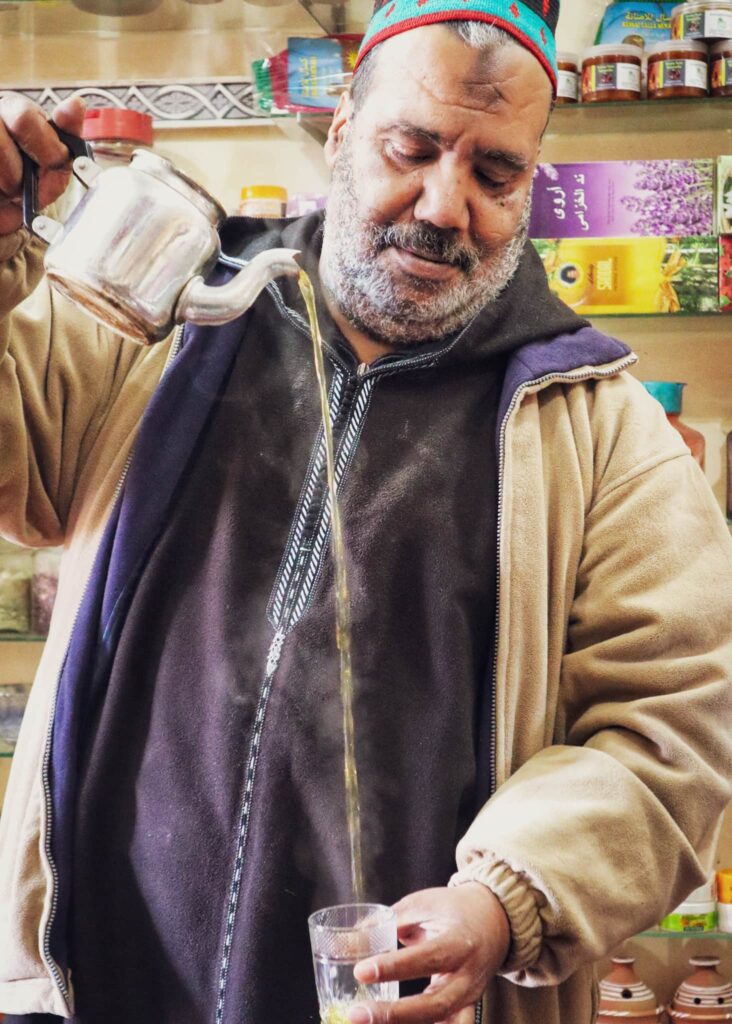 A Moroccan man pouring tea into a glas.