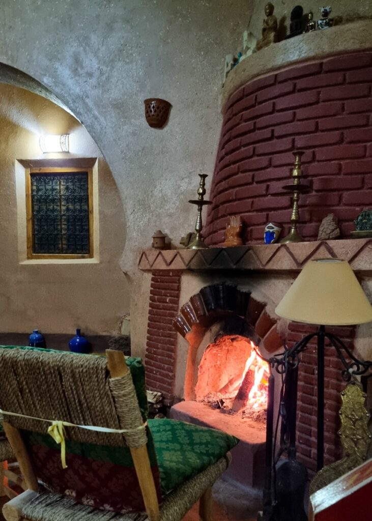 A lit fireplace with chairs in front at Riad Paradise of Silence in Ait Ben Haddou.