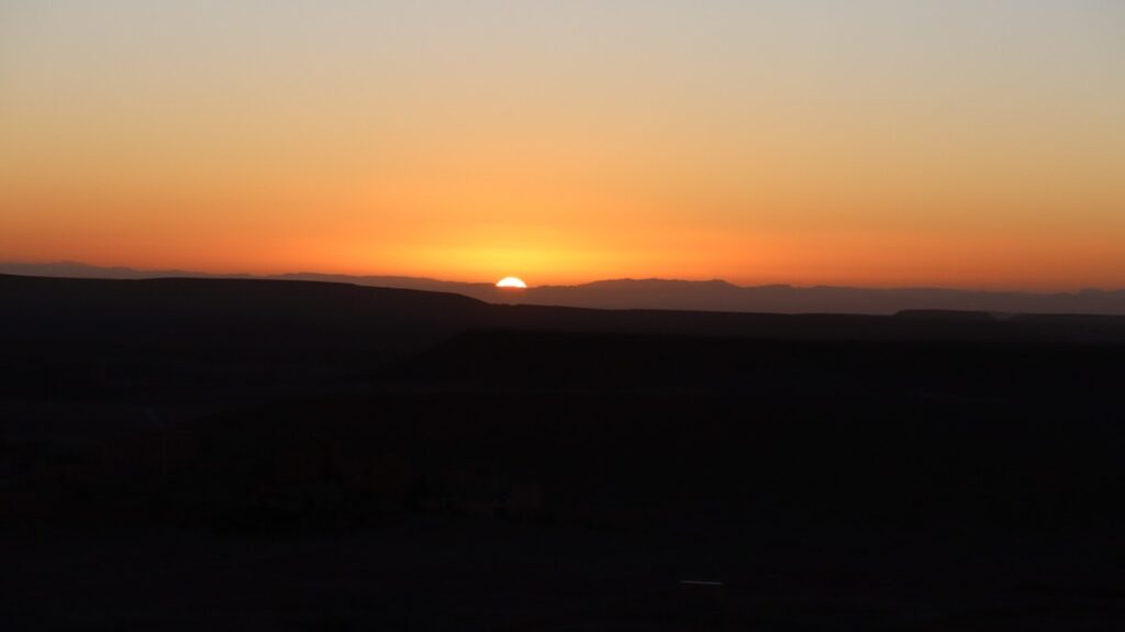 Sun showing up behind mountains in Morocco.