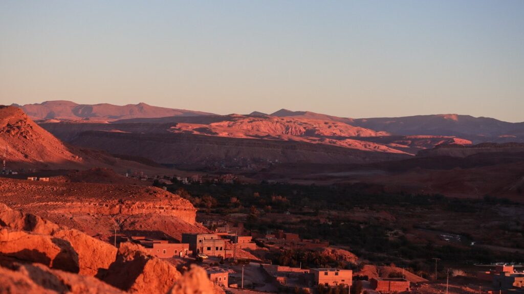Ait Ben Haddou's new town and surrounding landscape in the red light of the sunrise.