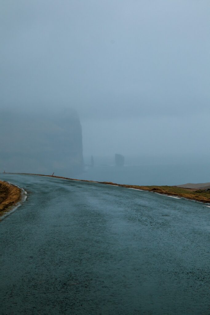 Rising and Kellingin sea stacks barely visible through fog. Road in front.
