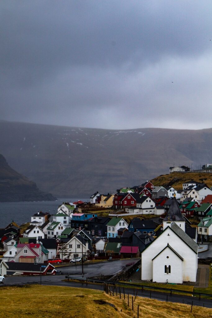 White and colourful wooden houses in Eið on the Faroe Islands on a rainy day.