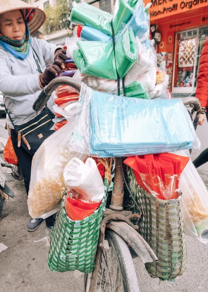 A female street vendor of Hanoi organising her goods on her bike.