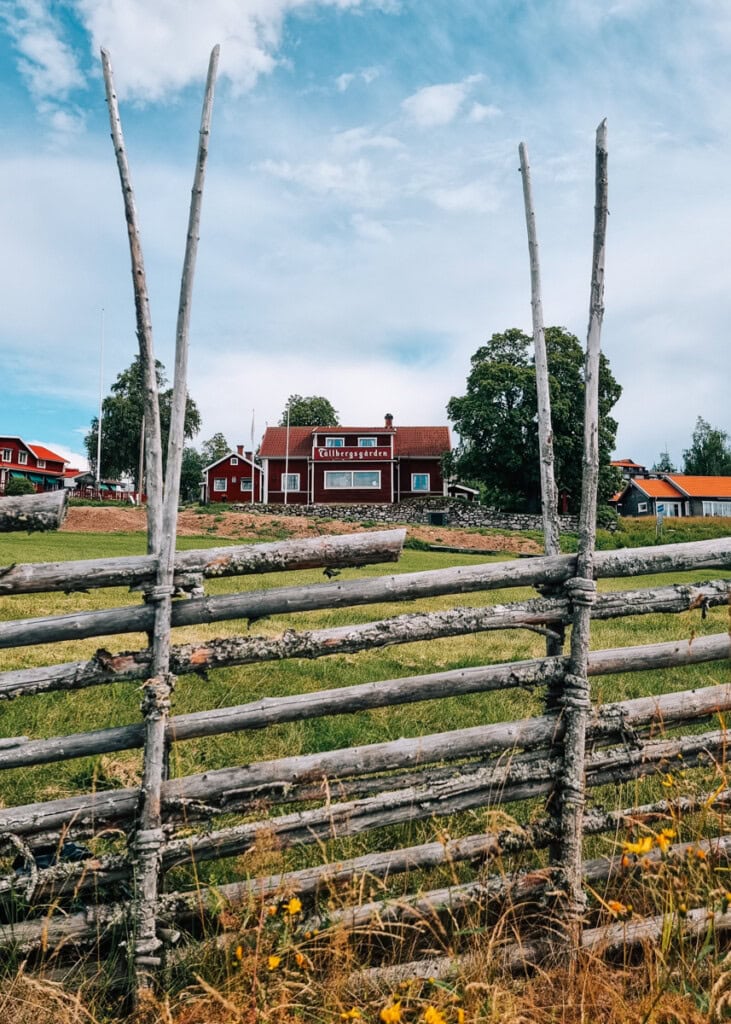 A traditional wooden fence in front of red and white houses in Dalarna.