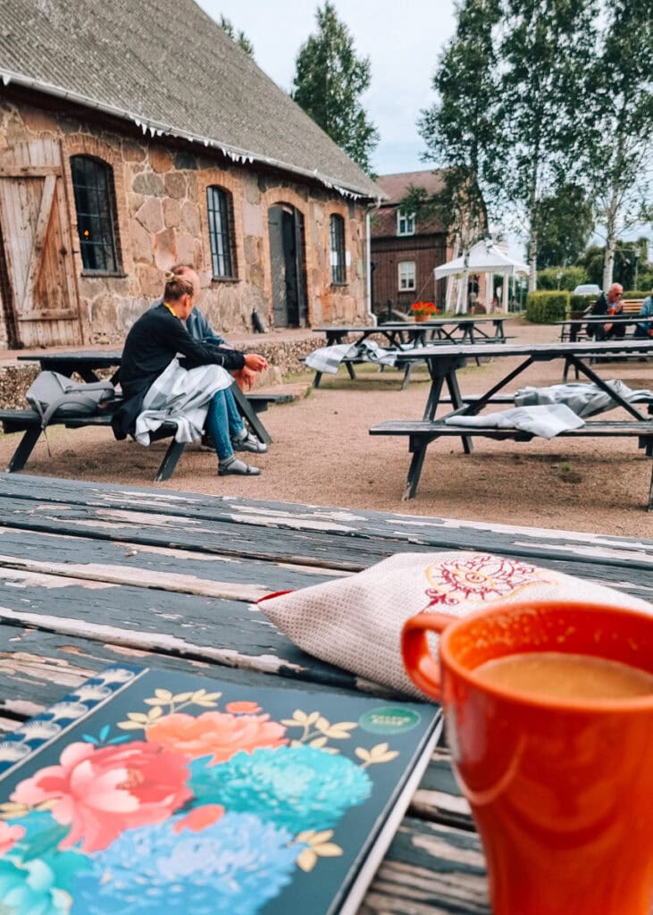 Notebook and coffee on a table outside Bläsinge Farms old farm buildings.