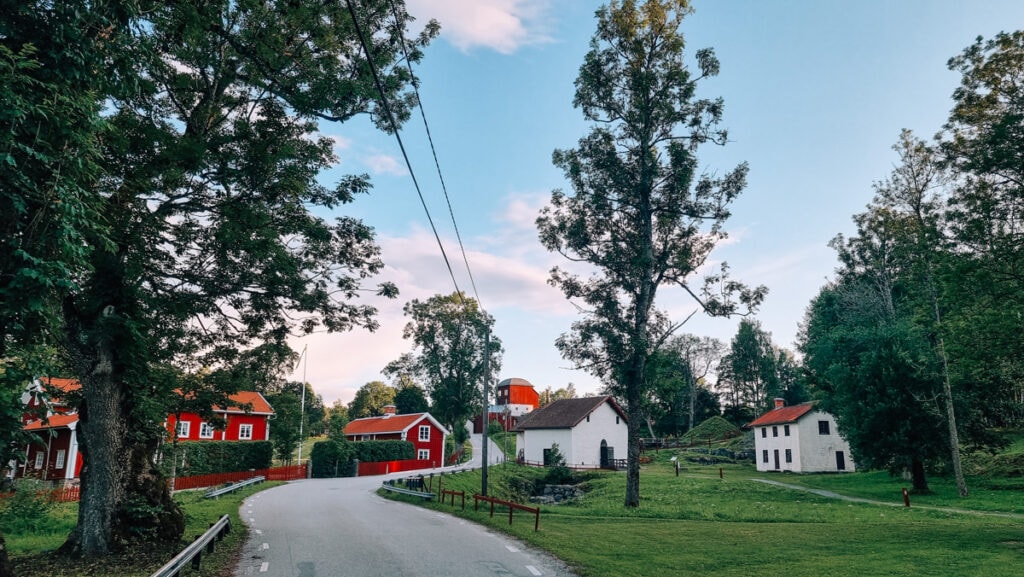 Pershyttan outdoor museum in Sweden. Red and white houses and mining buildings in between green grass and trees.