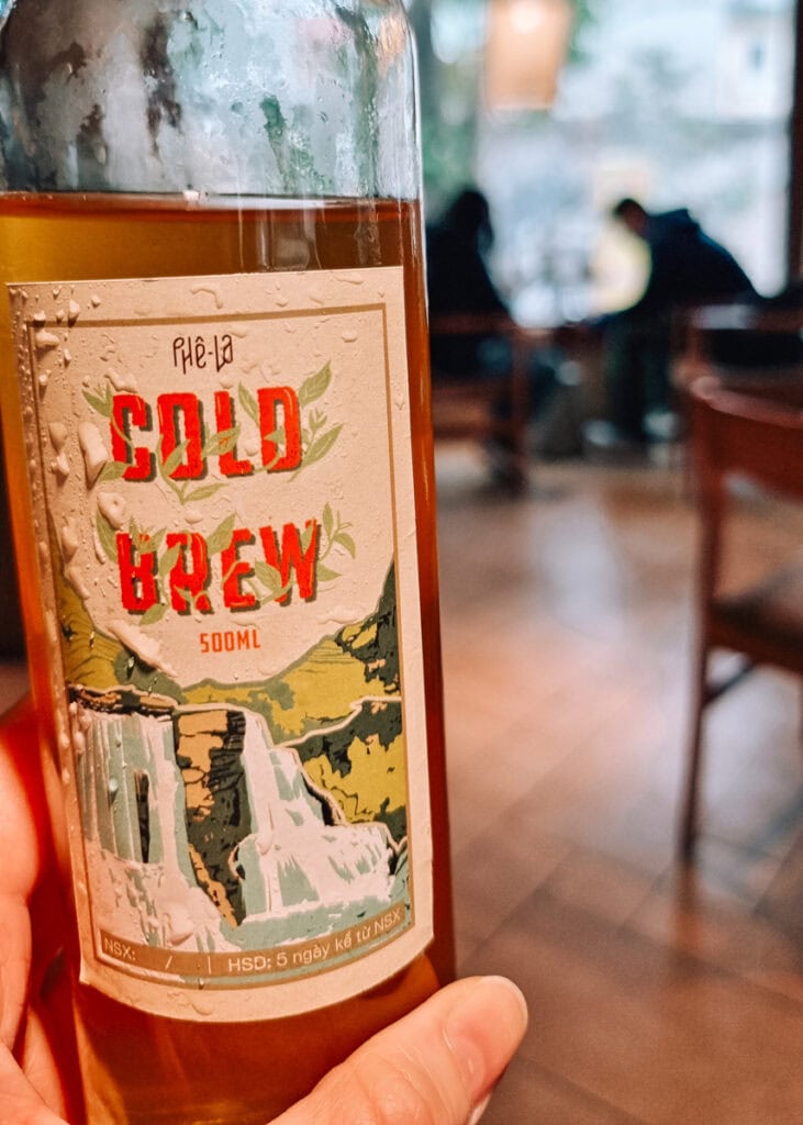 A glass bottle of cold brewed tea held up inside a café in Hanoi.