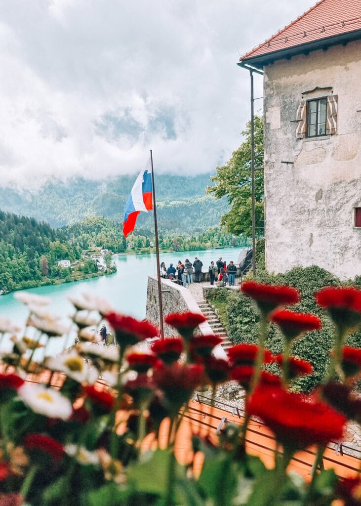 View from a balcony at Bled Castle. Flowers in front and the castle and lake Bled in the background.