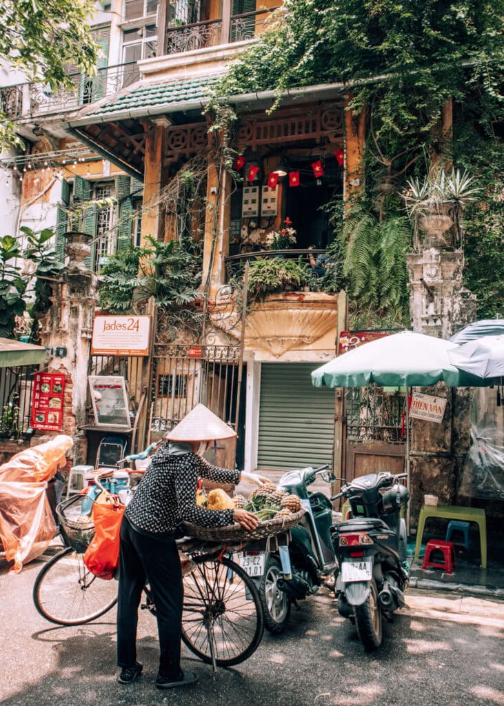 A street seler in Hanoi re-arranging pineapples on her bike outside Loading T Café.