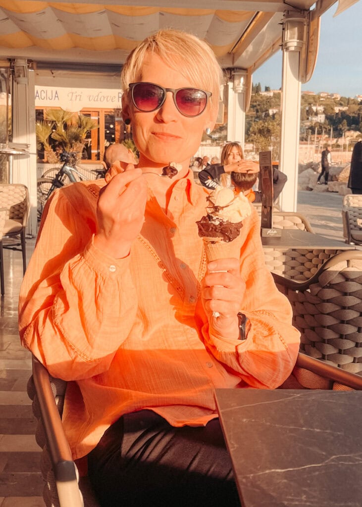 A woman enjoying an ice cream at sunset in Piran.