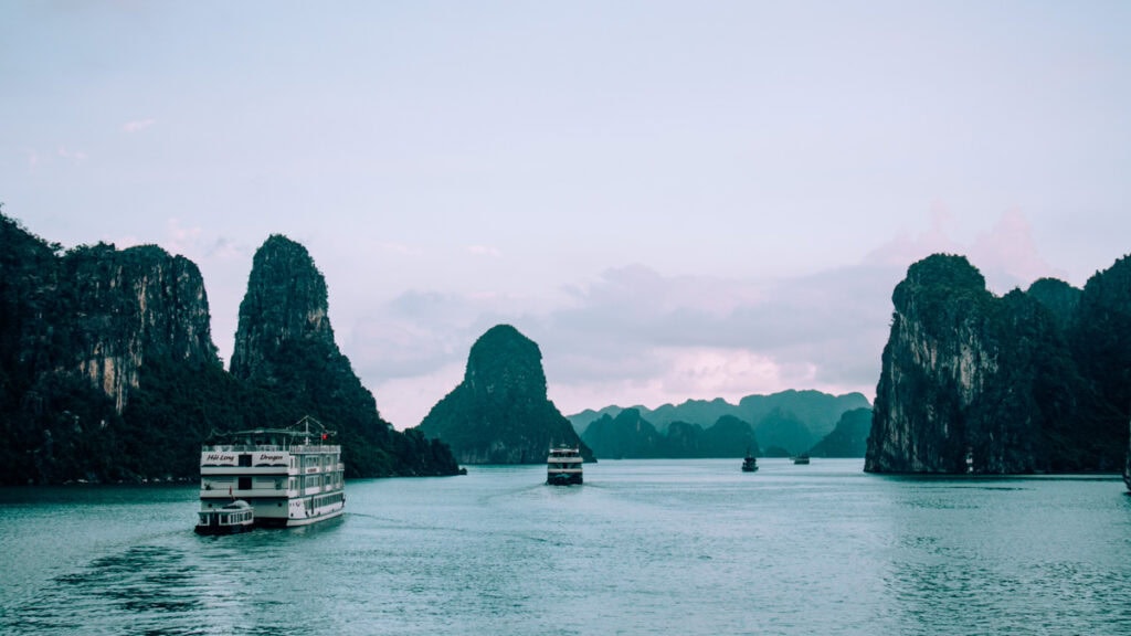 Halong Bay landscape with junk boats cruising between limestone carsts.