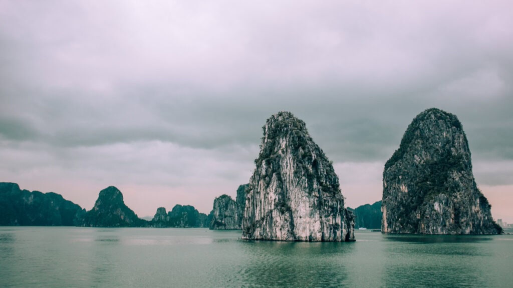 Limestone karsts in Halong Bay in dark, gloomy weather.