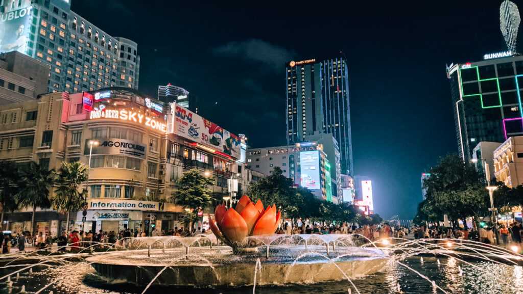 Night scene in Ho Chi Minh City. Lotus water fountain in front of tall buildings.