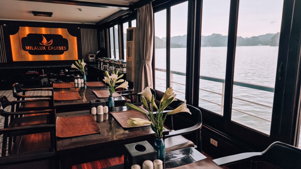 Interior photo of the elegant restaurant on the MilaLux ship. Halong bay seen outside the windows, the buffet seen at the back.
