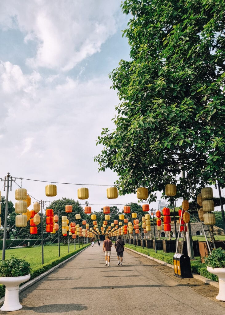 Two tourists walking under lanterns inside the Imperial Citadel of Thang Long.