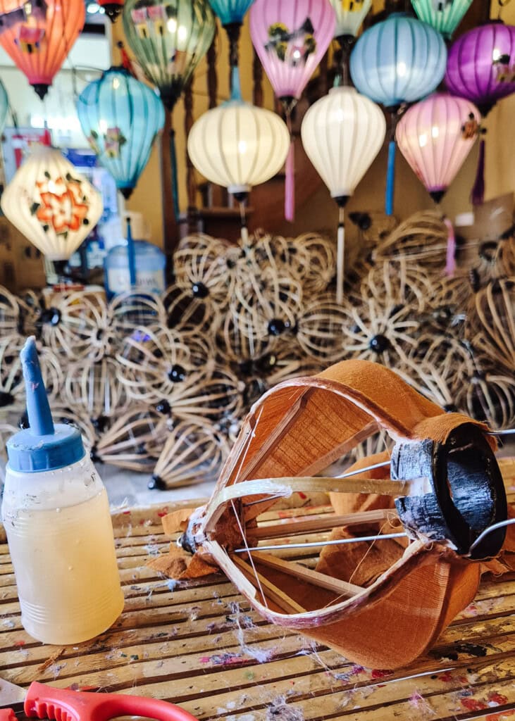 A lantern-in-the-making on a table. Frames and lanterns seen behind.