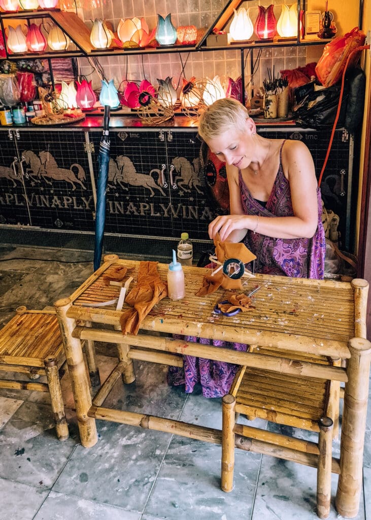 Anne (me) stretching fabric on a lantern frame inside a shop.
