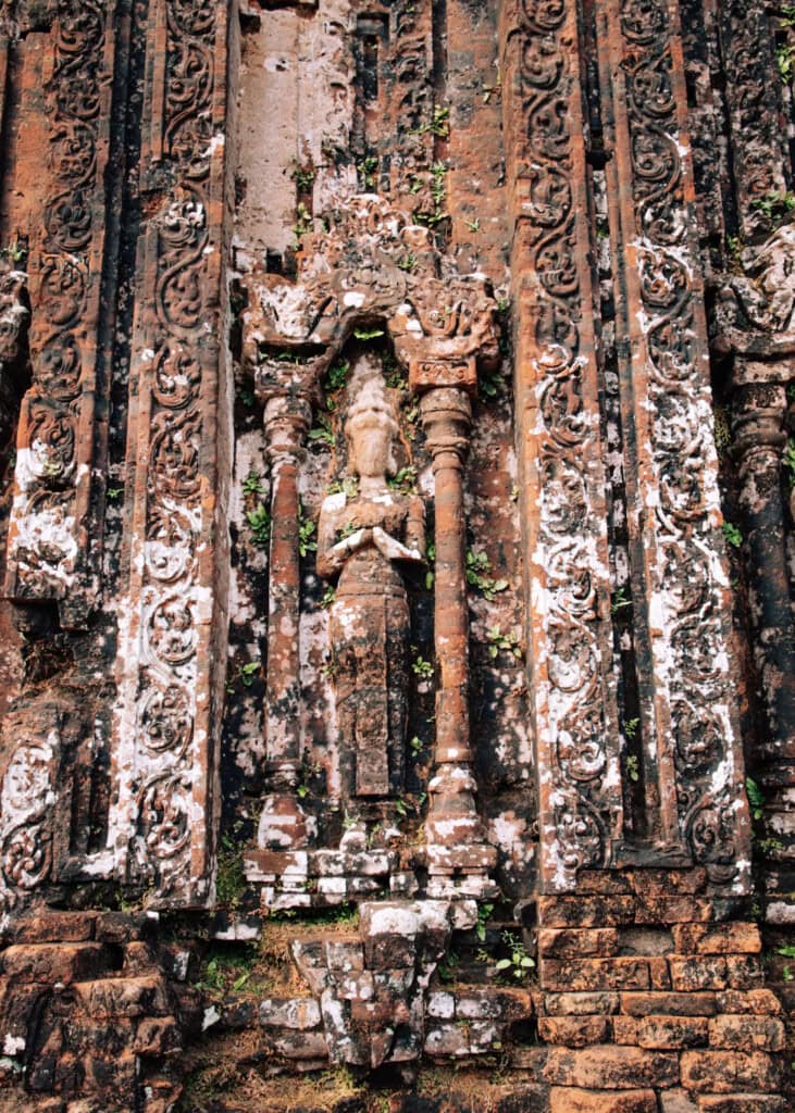 A detail of a temple at My Son showing a female figure between intricate stone carvings.