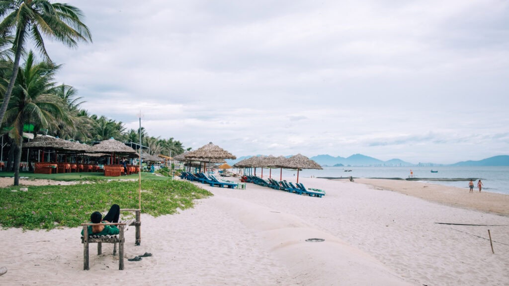 A man relaxing on a bench at Cua Dai beach.