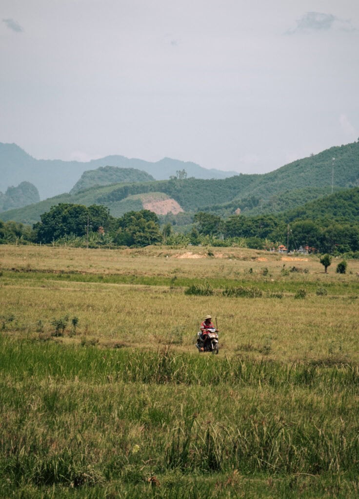 A man driving a motorbike through a green field.