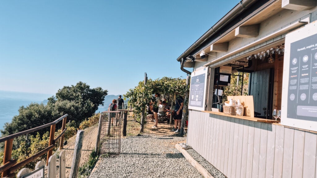 A small bar next to the trail, people sitting under vines.