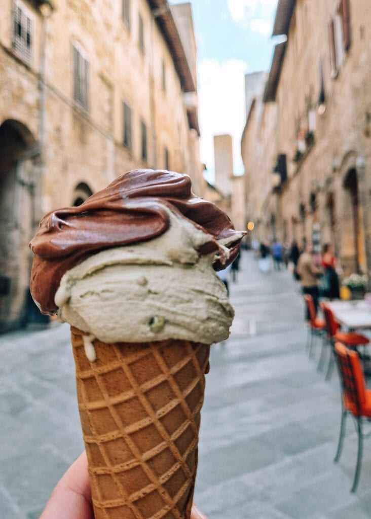 A gelato cone held up on a street inside San Gimignano.