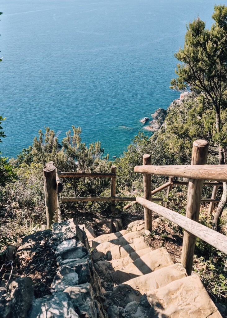Steep staircase going down a hill with the sea below.