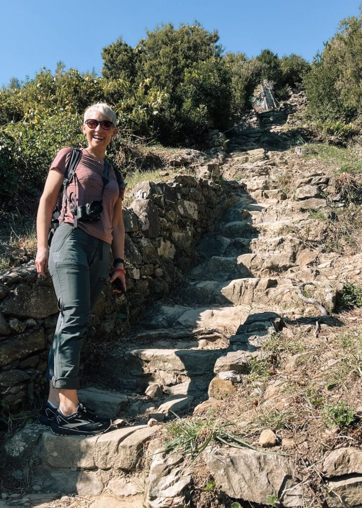 Me standing on the first step of an uneaven staircase of rock on the trail.