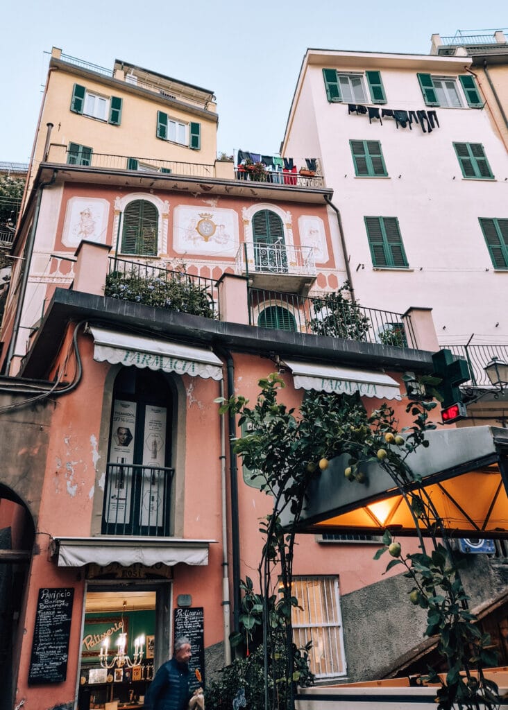 Typical buildings stacked on top of each other in Riomaggiore. A man leaving a bakery.