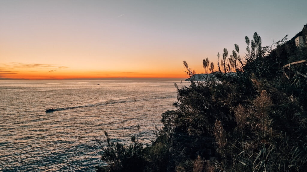 Sunset photo from Riomaggiore, a boat sailing in front.