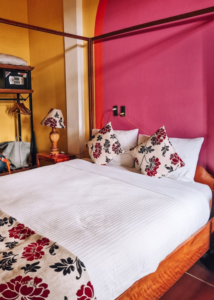 A double bed in a bright pink bedroom at Phong Nha Farmstay.
