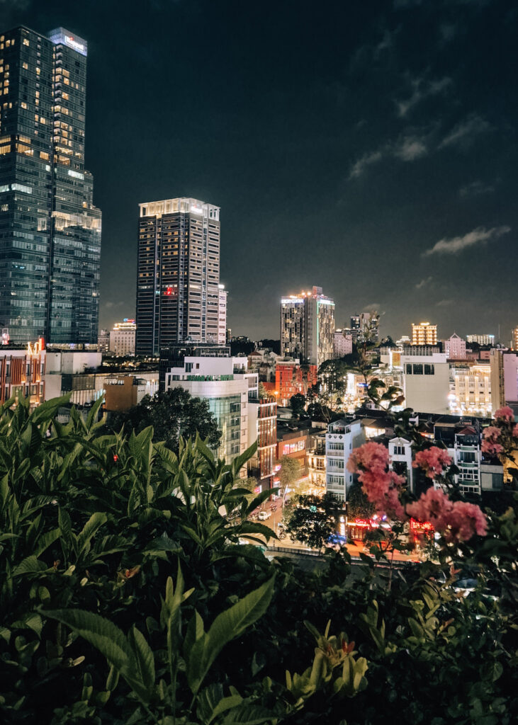 Saigon skyline seen from a rooftop terrace at night.