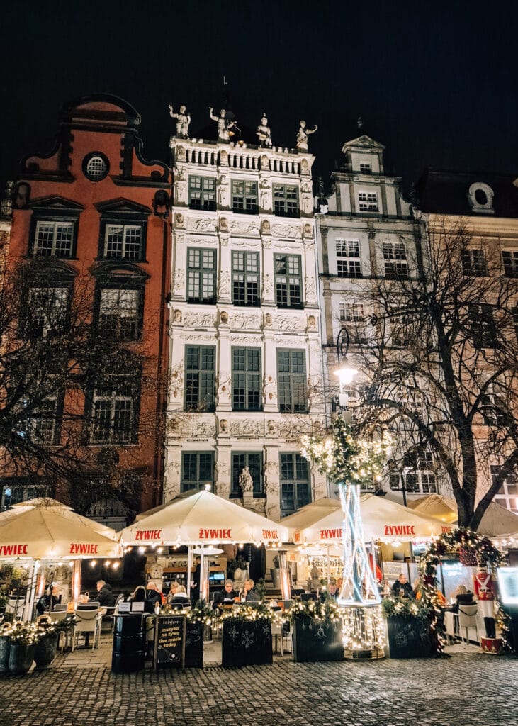 People sitting outside on restaurants along the Long Market in front of typical Hansa style buildings.